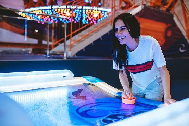 Young woman is having fun in amusement park playing table hockey