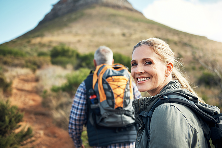 Portrait of a mature woman hiking with her husband through the mountains