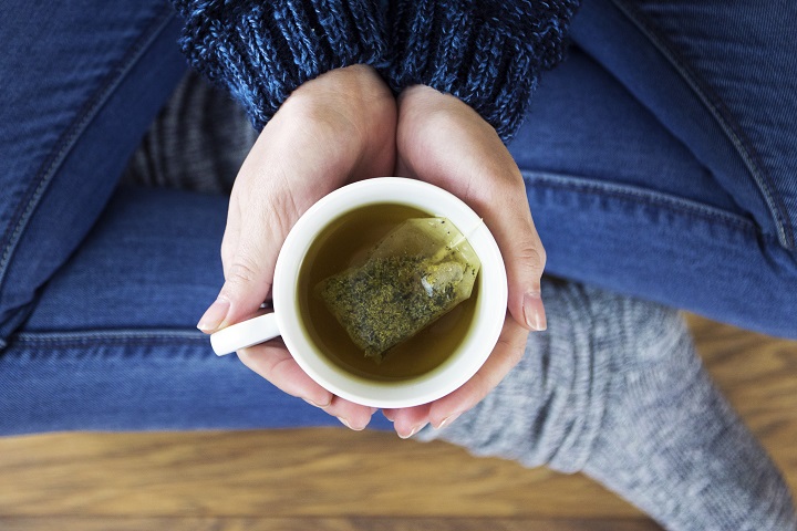 Birds eye view of a person holding a cup of peppermint tea.