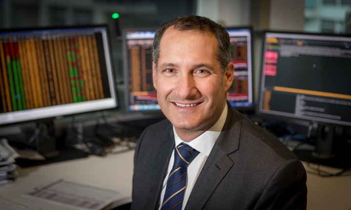 Photo of TelstraSuper Chief Investment Officer Graeme Miller smiling at his desk