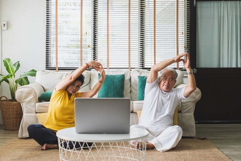 couple doing yoga in front of laptop in the lounge