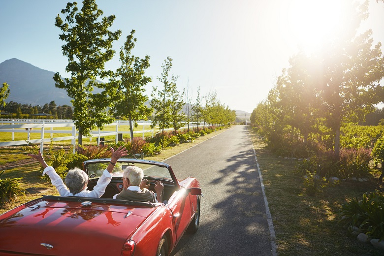 couple driving in a red sports car down a country lane