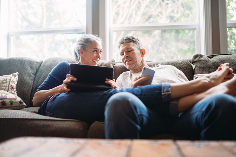 couple sitting on the couch with phone and laptop