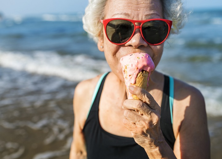 woman eating an icecream on the beach with red sunglasses