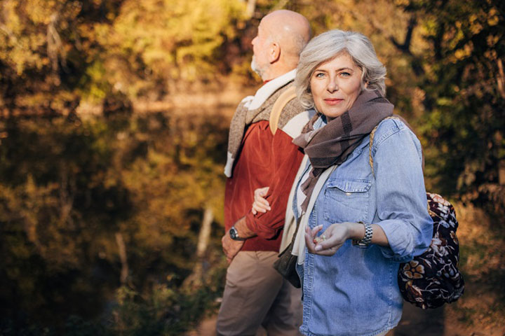 Man and woman happy mature couple standing by the river in nature on a beautiful autumn day